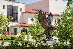 Red Hawk Statue in front of campus building on sunny day.